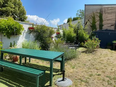 a green picnic table sitting in a garden at Côté Court in LʼIsle-sur-la-Sorgue