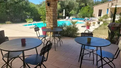 a patio with tables and chairs next to a pool at Maison d'Hôtes & Spa La Chêneraie-Provence Ventoux in Saint-Didier