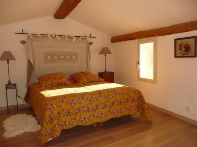 a bedroom with a bed with a yellow bedspread and a window at LOlivier sur le Toit in LʼIsle-sur-la-Sorgue