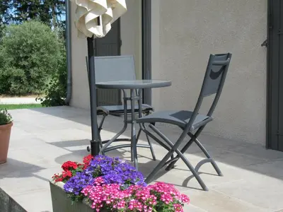 two chairs and a table and flowers on a patio at LA MASTRONA in Saumane-de-Vaucluse