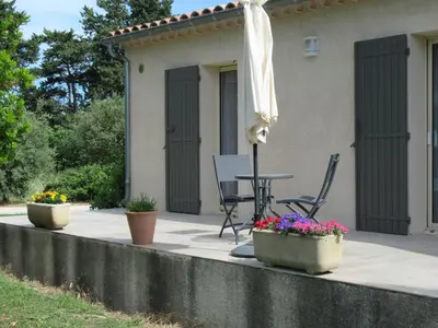 a patio with a table and an umbrella and flowers at LA MASTRONA in Saumane-de-Vaucluse