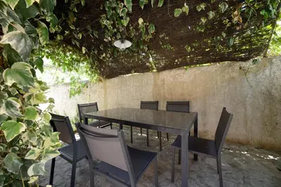a table and chairs with ivy growing on a wall at La Petite Maison - Mas des Sous Bois in Ventabren