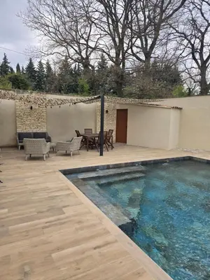 a patio with a swimming pool and a table and chairs at Un petit coin de Bali avec SPA et piscine privés in Carpentras