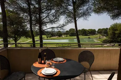 a table and chairs on a patio with a view of a golf course at LA PERLE DE PROVENCE-Magnifique Vue CLIM LINGE Golf Saumane 6P Piscine Tennis in Saumane-de-Vaucluse