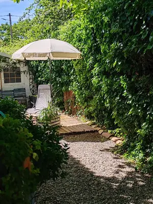 a patio with an umbrella and a chair and a bench at LE PETIT JARDIN ... in LʼIsle-sur-la-Sorgue