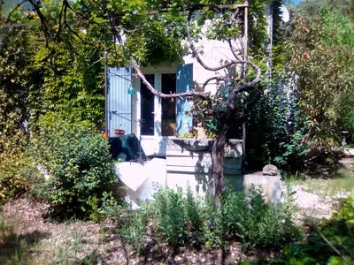 a dog sitting in front of a house with a blue door at Le Domaine de Belle in LʼIsle-sur-la-Sorgue