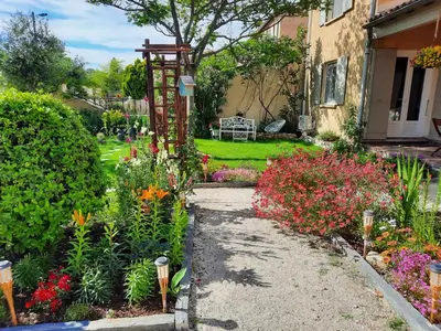 a garden with colorful flowers and a house at La Maison du Chemin des Prairies in Morières-lès-Avignon