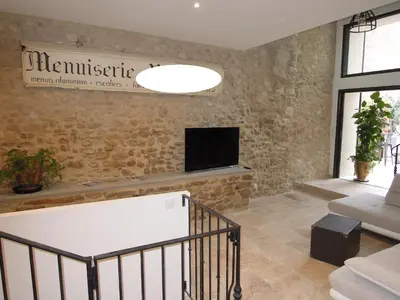 a living room with a tv on a stone wall at La Bourgade in Céreste