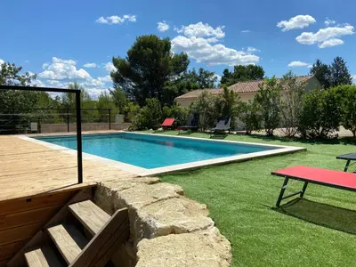 a swimming pool in a yard with a red table at Villa la Provence, Luxe, Confort et Joie de Vivre in Carpentras