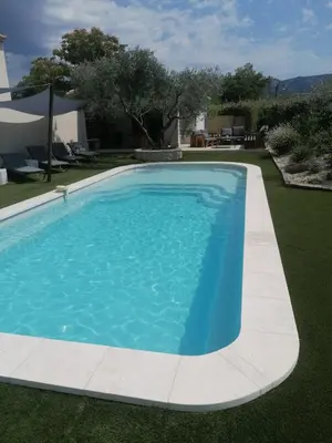 a swimming pool with blue water in a yard at L'atelier de Guytou et Spa in Cheval-Blanc