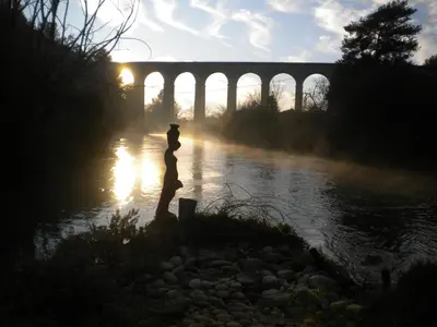 a person standing in front of a river with a bridge at Appartement à FONTAINE DE VAUCLUSE in Fontaine-de-Vaucluse