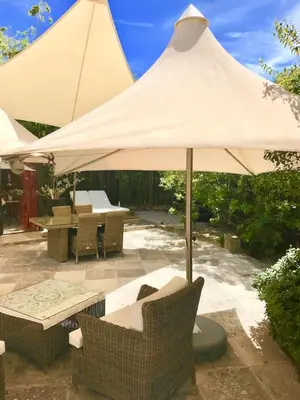 a patio with a table and a large umbrella at LASUITE Domaine Bertuli, heated Pool, Aircon in Oppède