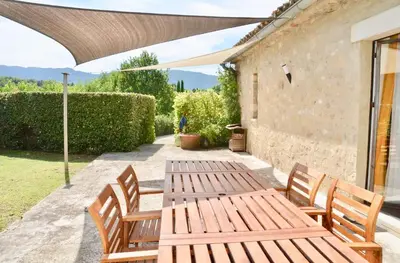 a wooden table and chairs on a patio at Les Cerisiers maison bertuli climatisé, Piscine chauffée, lit King size, classé 5 étoiles in Oppède