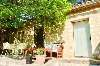 a patio with a table and chairs and a table and a tree at Les Cerisiers maison bertuli climatisé, Piscine chauffée, lit King size, classé 5 étoiles in Oppède