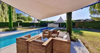 a patio under an umbrella next to a swimming pool at Les Cerisiers maison bertuli climatisé, Piscine chauffée, lit King size, classé 5 étoiles in Oppède