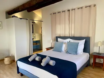 a bedroom with a large bed with blue and white pillows at Villa Velleron - Bed and Breakfast in Velleron