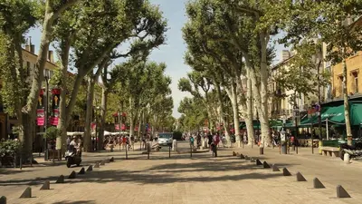 a street with trees and people walking on the sidewalk at Appartement T2 Cosy sur Aix in Aix-en-Provence