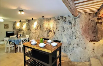 a dining room with a table and a stone wall at 2 Bedroom Amazing Home In Apt in Apt