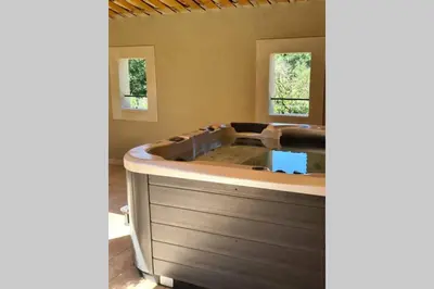 a jacuzzi tub in a room with two windows at Le Cabanon de Nans. Gîte de charme en Provence. in Grans