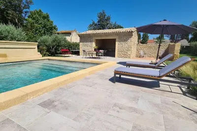 a swimming pool with two lounge chairs and an umbrella at Le Cabanon de Nans. Gîte de charme en Provence. in Grans