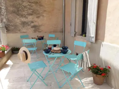 a patio with blue chairs and a table and a table and chairs at MAISON BOURGUES in Lioux