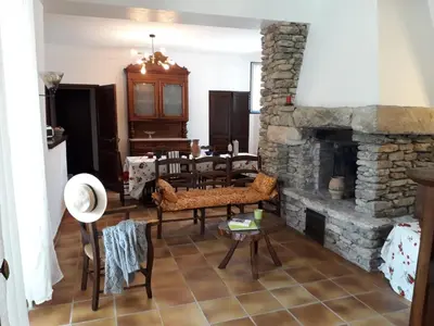 a living room with a stone fireplace and a table at MAISON BOURGUES in Lioux