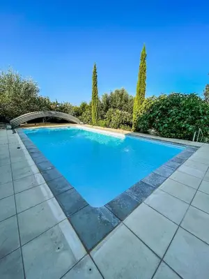 a blue swimming pool with trees in the background at Studio avec kitchenette du sentier des ocres in Roussillon