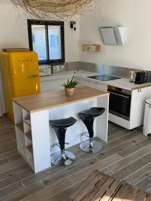 a kitchen with a counter and two stools at Petit nid douillet en Luberon avec spa in Ansouis