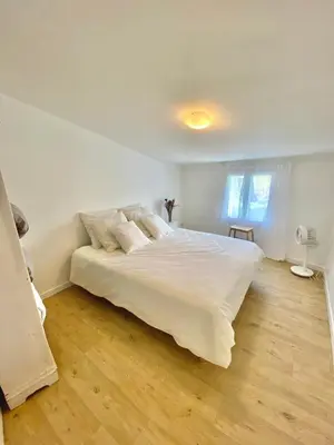 a bedroom with a large white bed and wooden floors at Il y a le Soleil, la Campagne et la Mer in Martigues