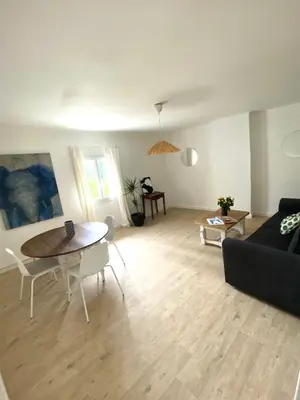 a living room with a black couch and a table at Il y a le Soleil, la Campagne et la Mer in Martigues