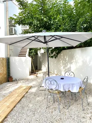a white table and chairs under an umbrella at Il y a le Soleil, la Campagne et la Mer in Martigues