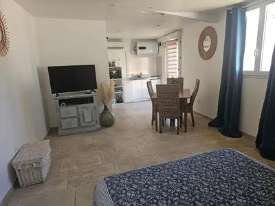 a living room with a table and chairs and a television at Tylyan in Le Thor