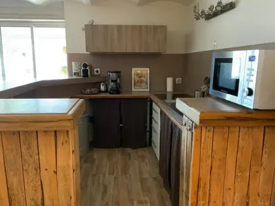 a kitchen with wooden cabinets and a microwave at Au petit bonheur in LʼIsle-sur-la-Sorgue