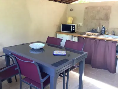 a dining room table with purple chairs and a kitchen at jardin d'antan in Ansouis