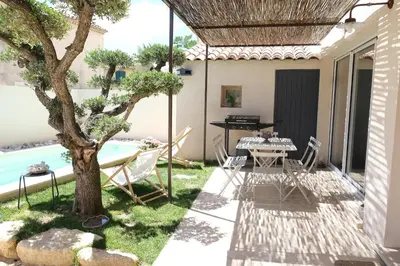 a patio with a table and chairs and a tree at charming house with private pool in the heart of the village of aureille in the alpilles, 6 people. in Aureille