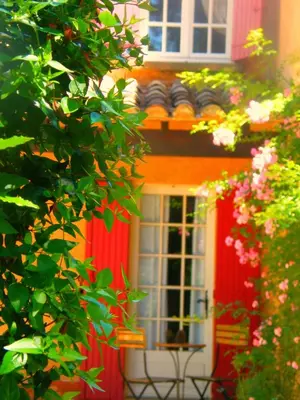 an orange house with a red door with a window at Logis Hôtel restaurant des Pins in Bédoin