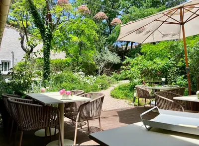 a patio with tables and chairs and an umbrella at Logis Hôtel restaurant des Pins in Bédoin