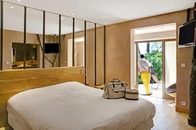 a bedroom with a bed and a person walking out the door at Logis Hôtel restaurant des Pins in Bédoin