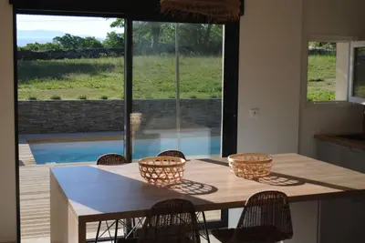 a kitchen with a table with chairs and a large window at Villa pleine campagne, piscine chauffée , Lubéron in Lacoste