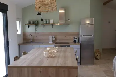 a kitchen with a wooden table and a stainless steel refrigerator at Villa pleine campagne, piscine chauffée , Lubéron in Lacoste