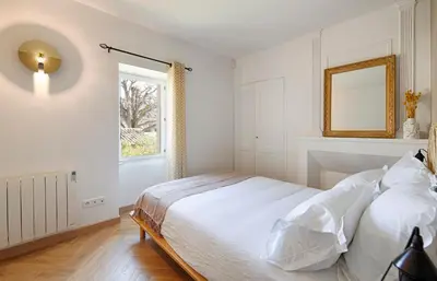 a white bedroom with a bed and a mirror at Le Mas des Sablières in Oppède
