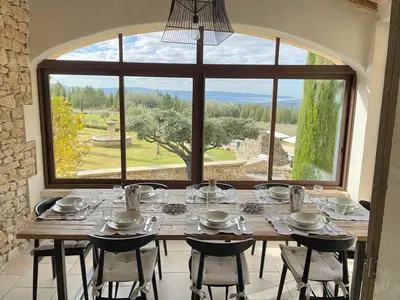 a large dining room table with chairs and a large window at Grands Abayers in Apt