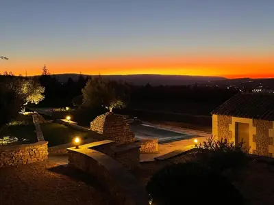 a view of a sunset from a house with lights at Grands Abayers in Apt