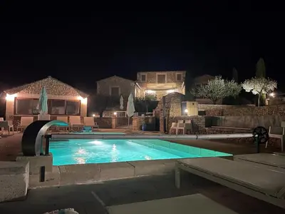 a swimming pool at night with a house in the background at Grands Abayers in Apt