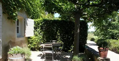 a table and chair under a tree next to a house at Domaine Faverot in Maubec