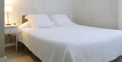 a white bed in a room with a night stand at Domaine Faverot in Maubec