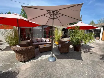 a large tan umbrella and chairs and a couch at Mas de la Butte Blanche in Orgon