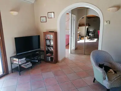 a living room with a television and a chair at Maison au calme entre vignes et Luberon in La Motte-dʼAigues