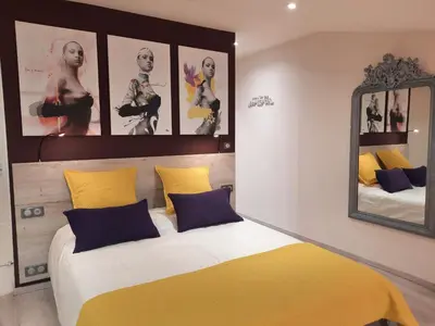 a bedroom with a bed with yellow and blue pillows at Le Loft sur les quais in LʼIsle-sur-la-Sorgue