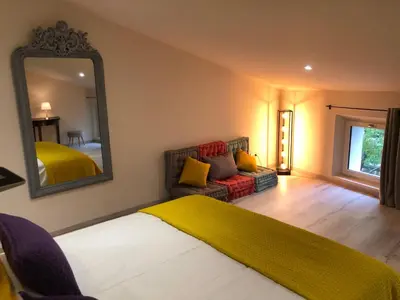 a bedroom with a bed and a mirror and a couch at Le Loft sur les quais in LʼIsle-sur-la-Sorgue